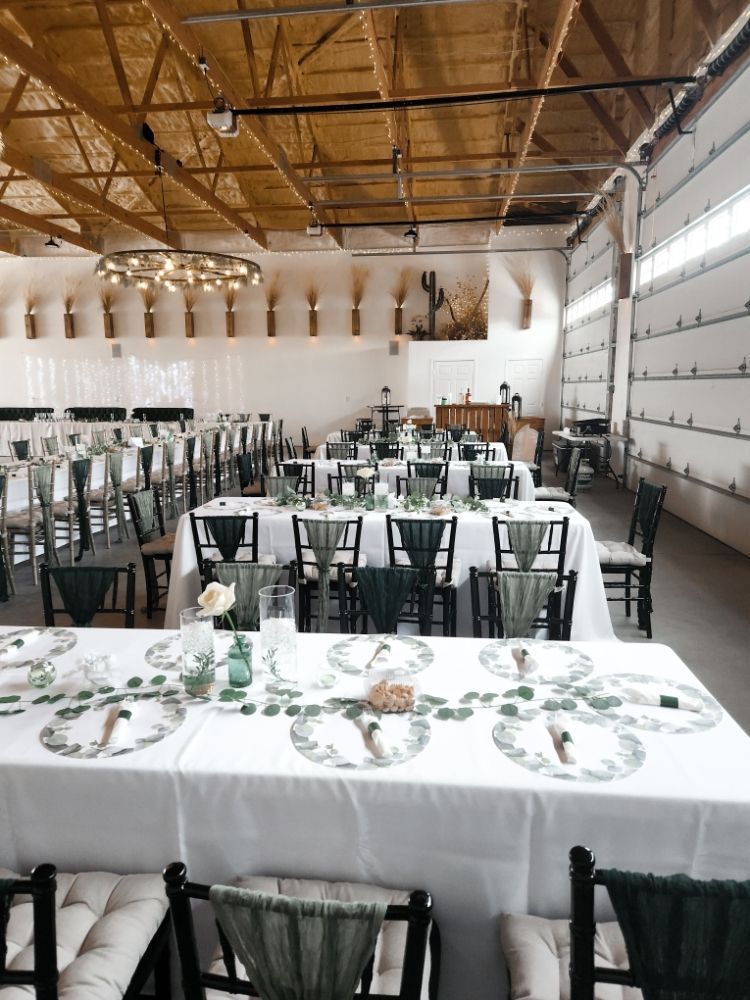Long banquet hall with white tablecloths, black chairs, and a wood-beamed ceiling