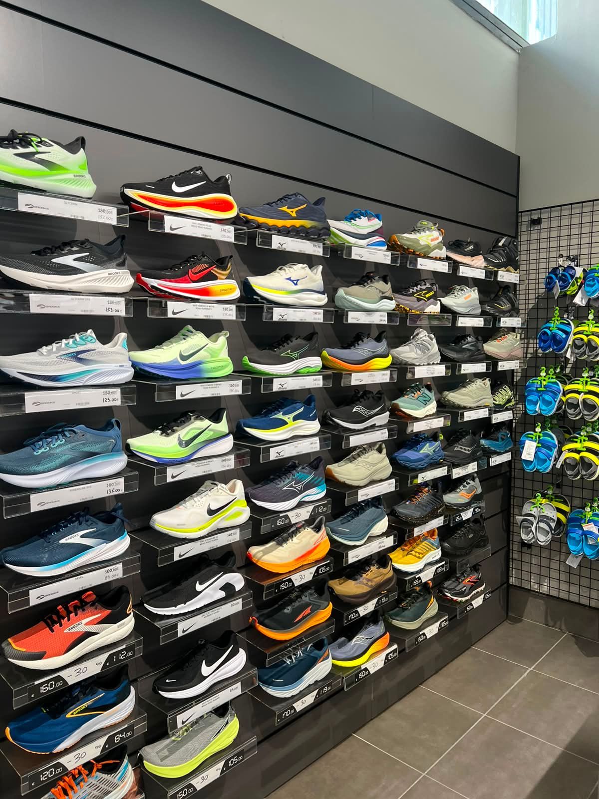 Parete espositiva di scarpe da running e calzature tecniche per tennis e padel dei migliori brand presso Sport Service a Forlì.