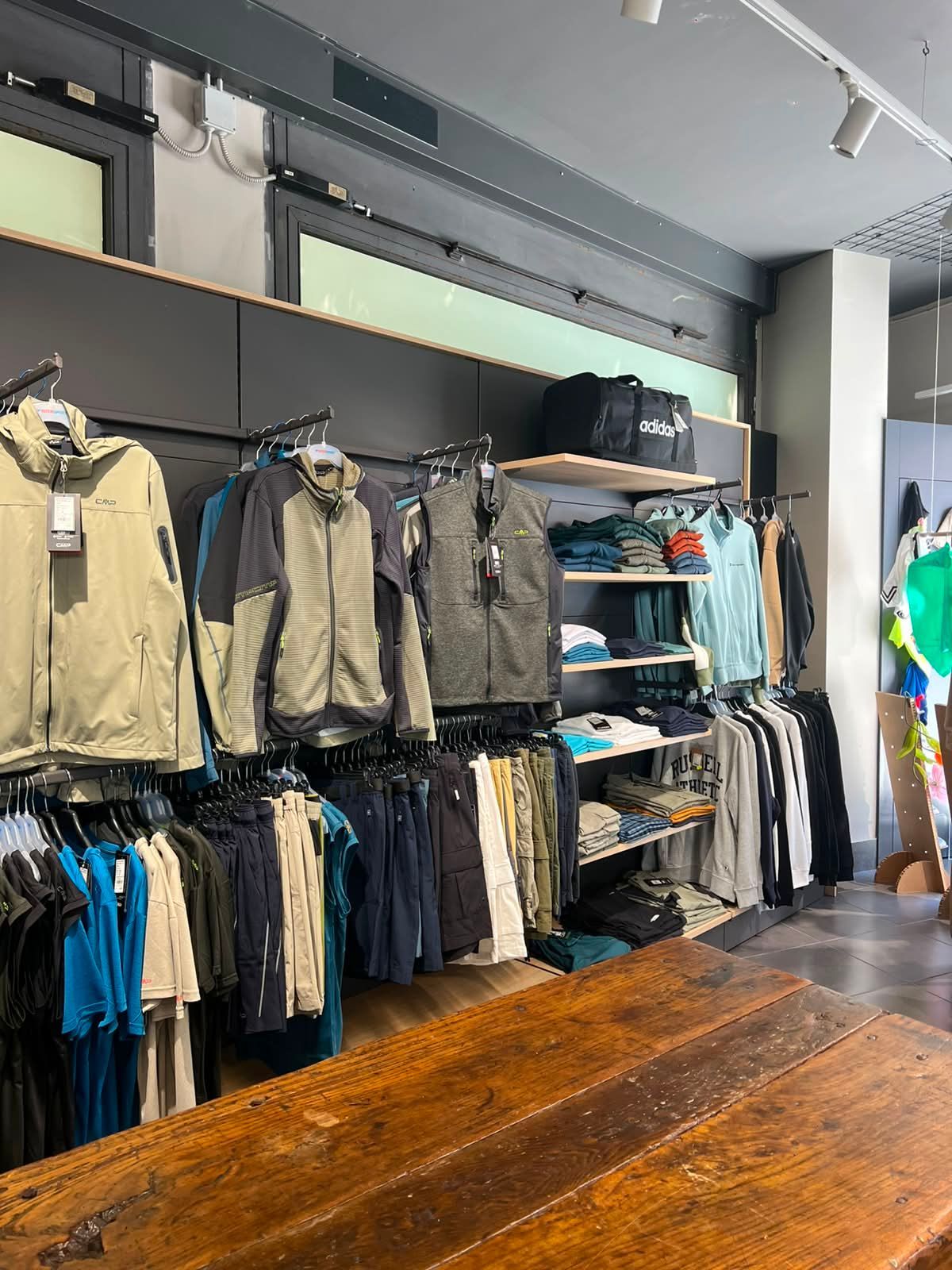 Assortimento di abbigliamento tecnico, giacche sportive e felpe da allenamento esposte nel negozio Sport Service a Forlì.