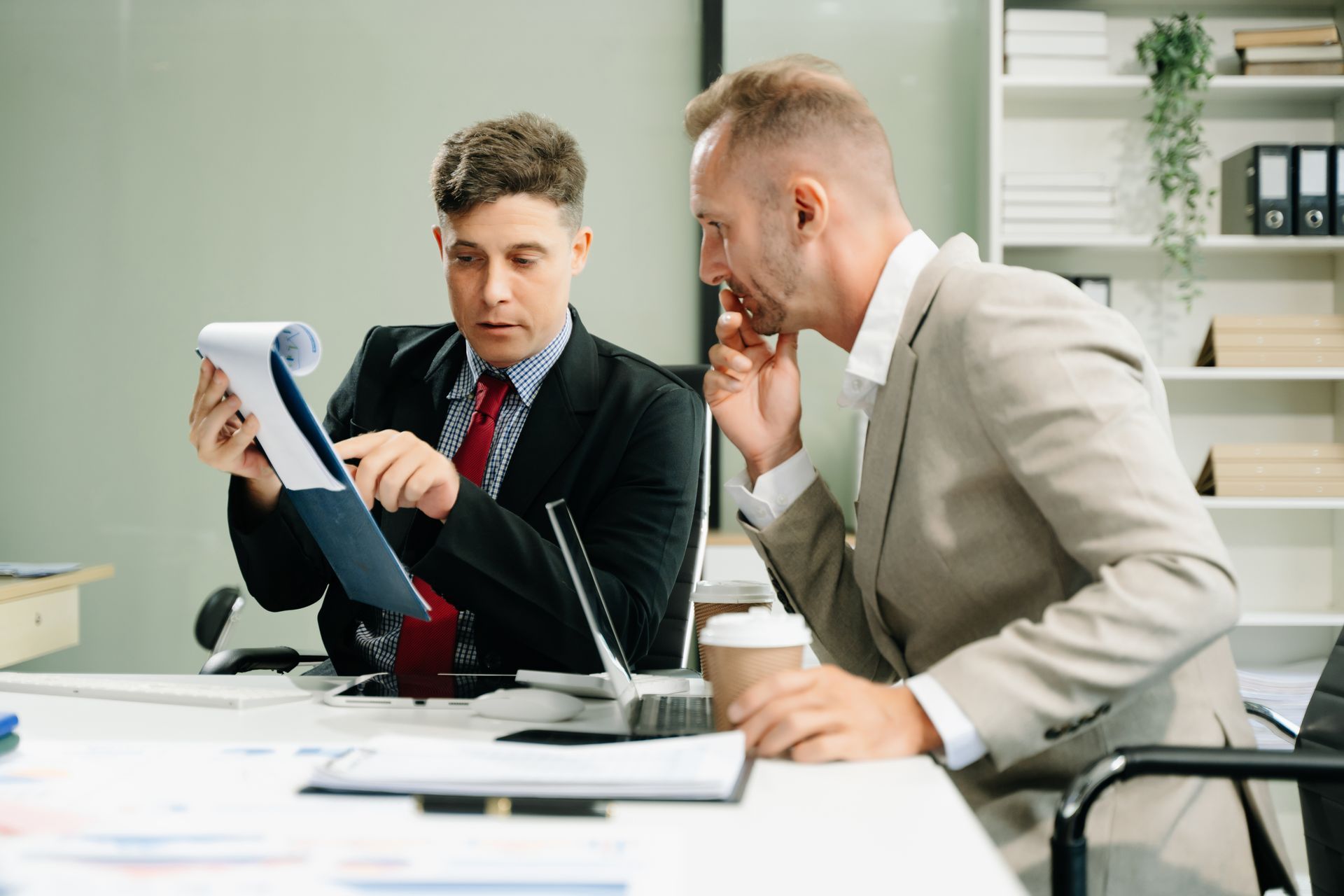 Two colleagues reviewing documents at a desk in a modern office