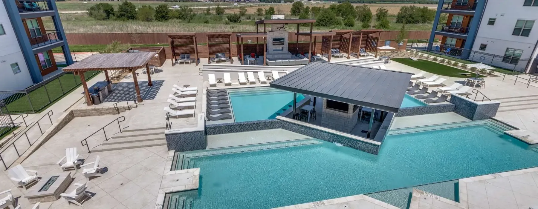 Outdoor swimming pool with swim-up bar and lounge chairs.