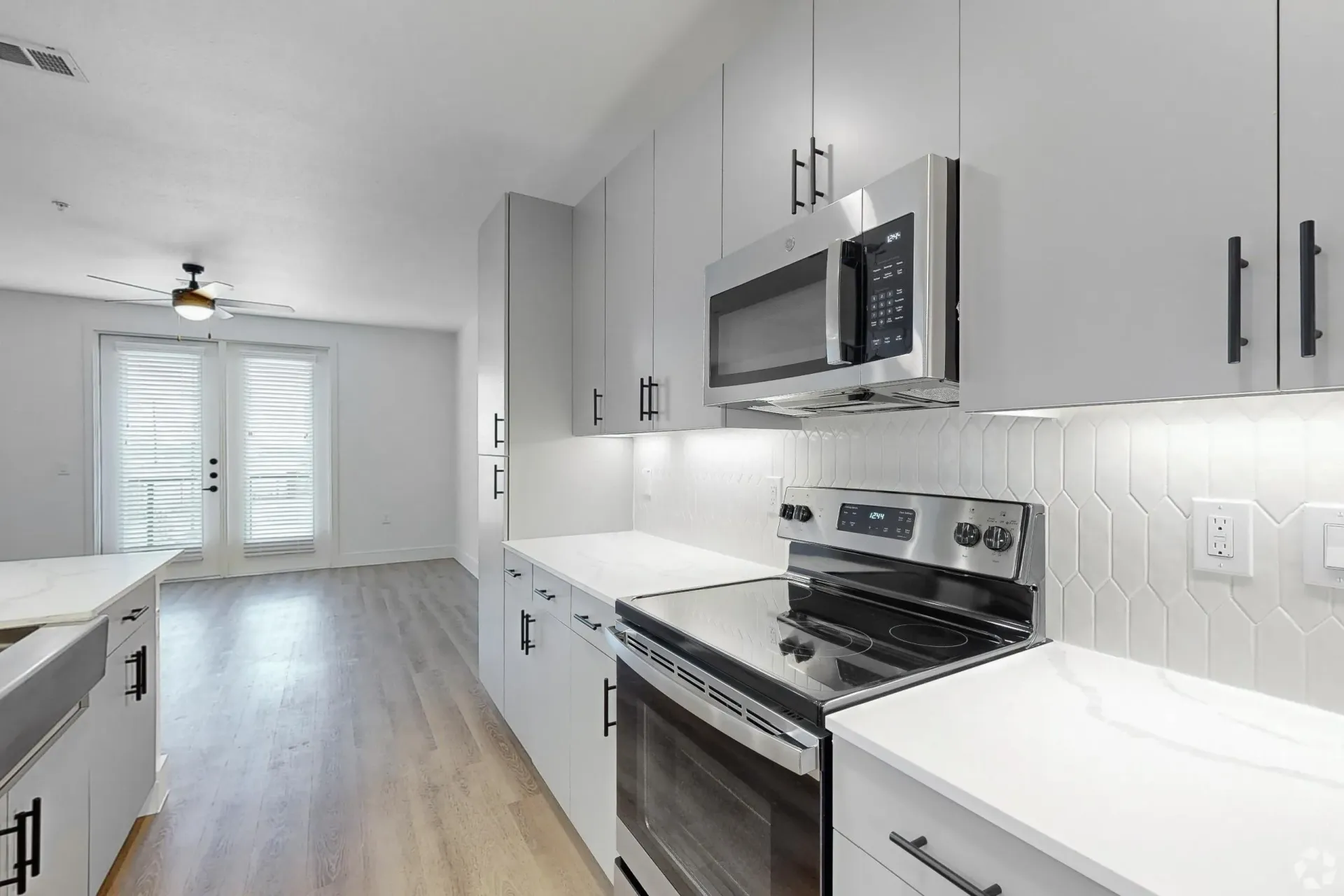 Modern kitchen with white cabinets, stainless steel appliances, and a large window.