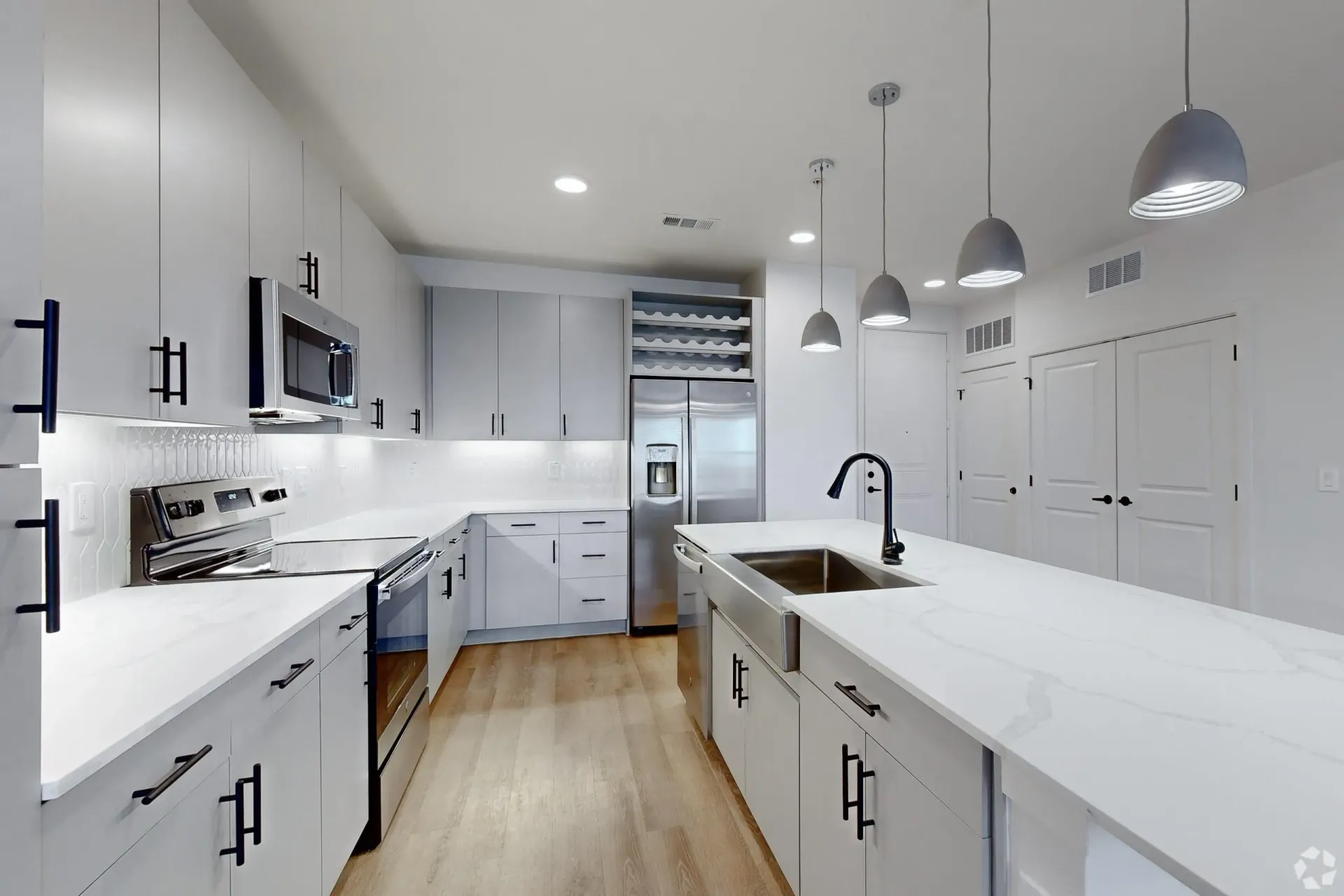 Modern kitchen with white cabinets, stainless steel appliances, and a large island with a sink.