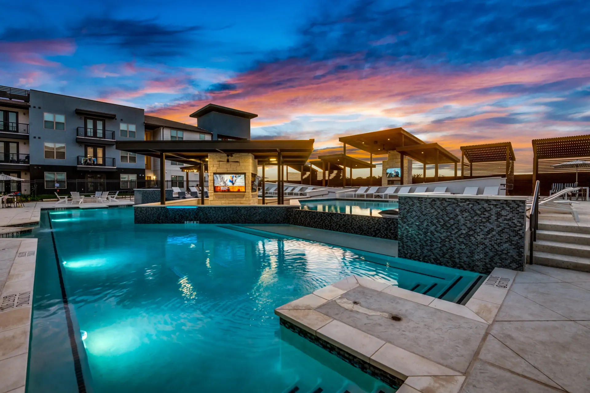Luxury swimming pool and lounge area at sunset.