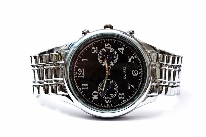 Primo piano di un orologio d'argento con quadrante nero su sfondo bianco.