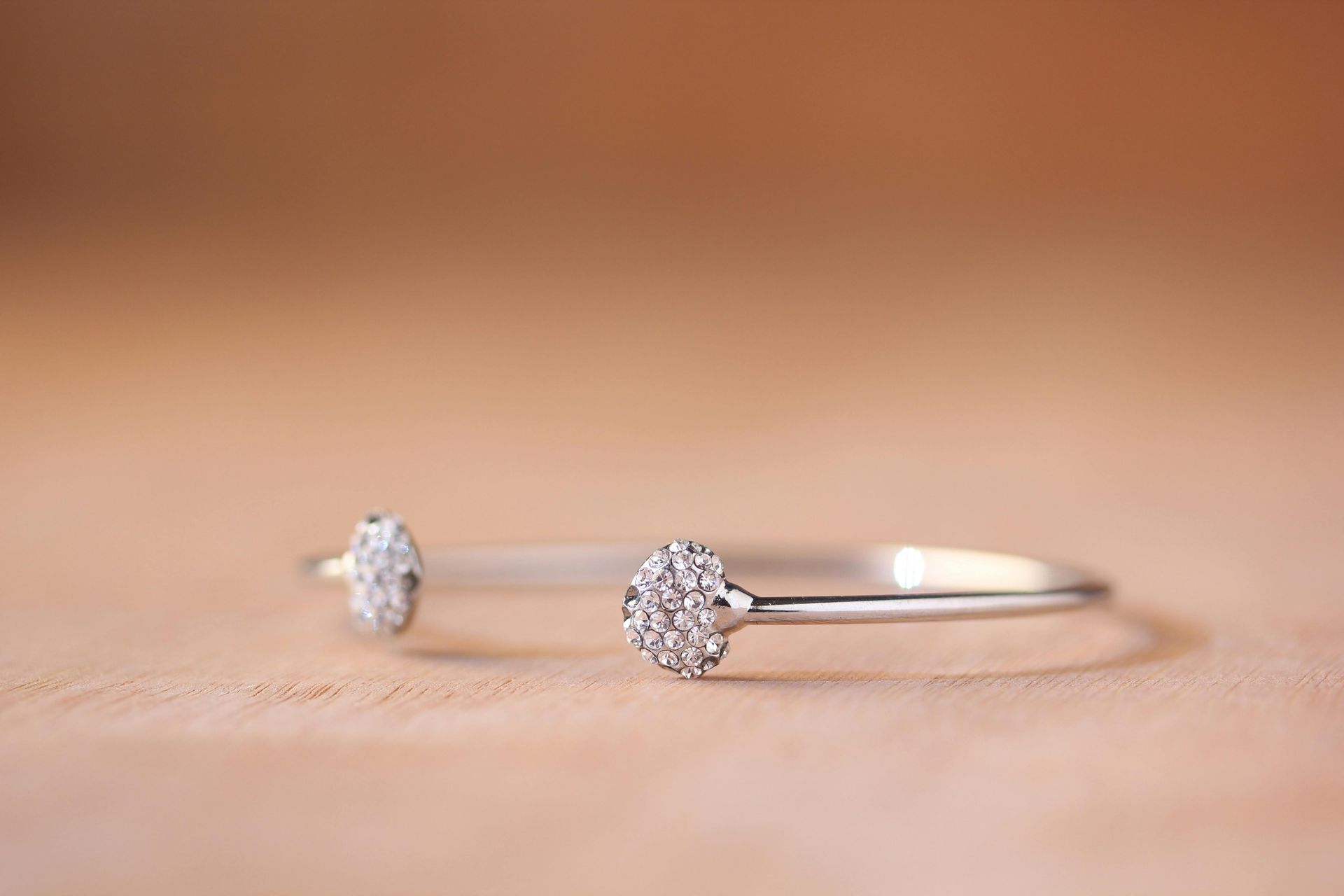 Primo piano di un braccialetto d'argento con diamanti su un tavolo di legno.