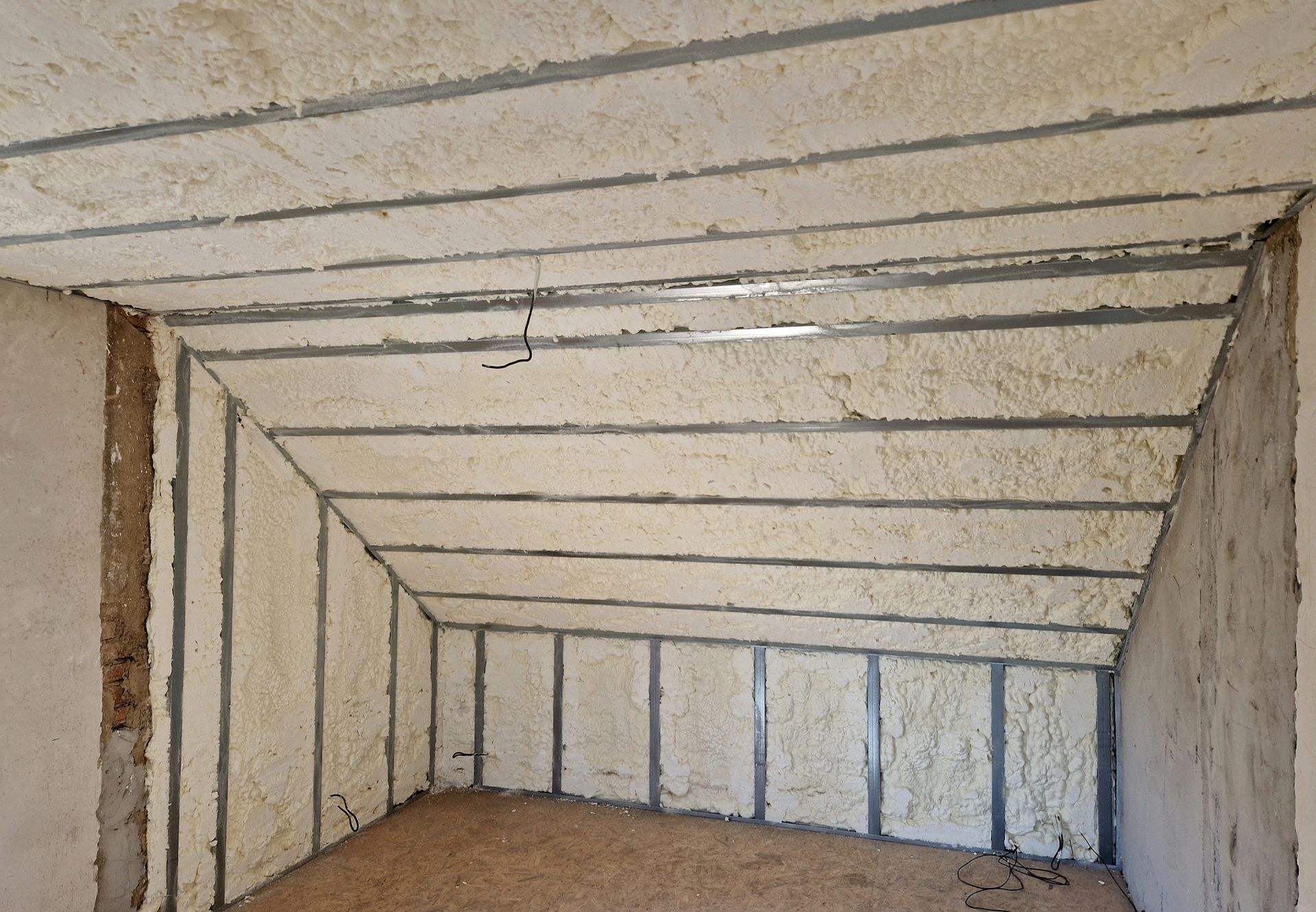 Closed-cell spray foam covering rafters and wall cavities to create an airtight attic space.