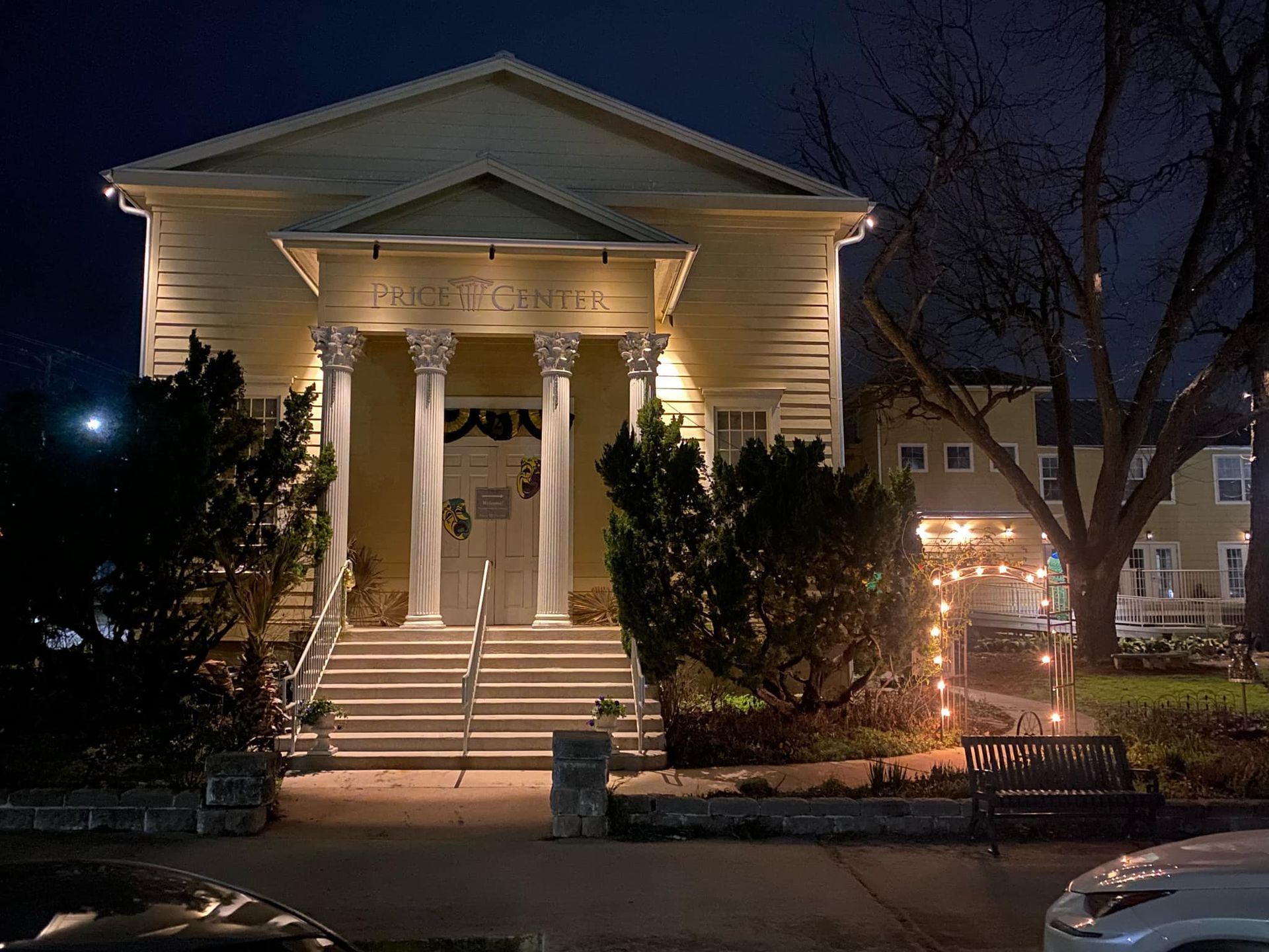Yellow building with columns, stairs, and decorative lights at night.