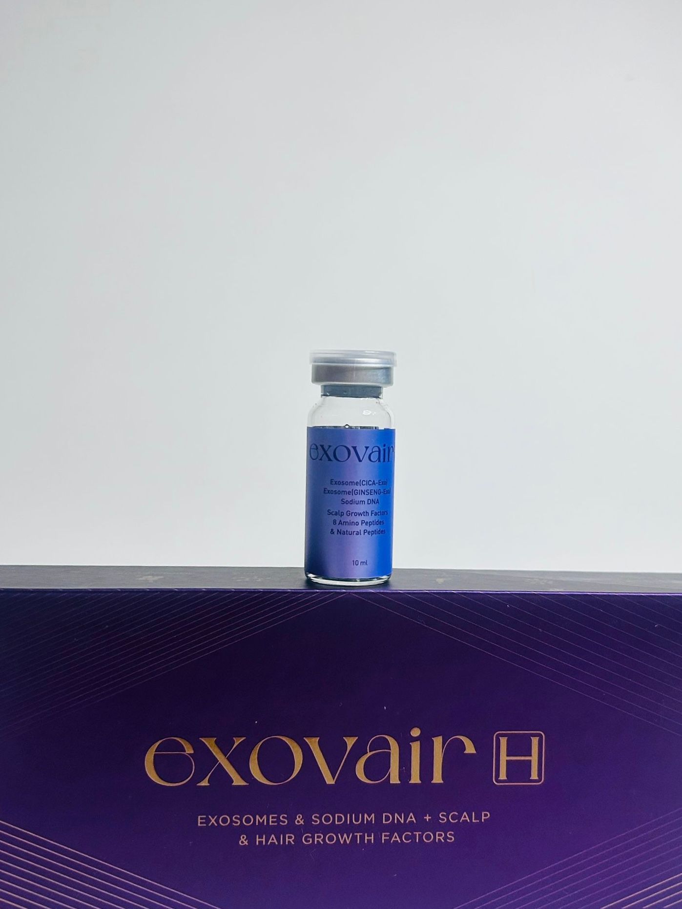 A vial of Exovair H hair growth treatment on a purple box against a white background.
