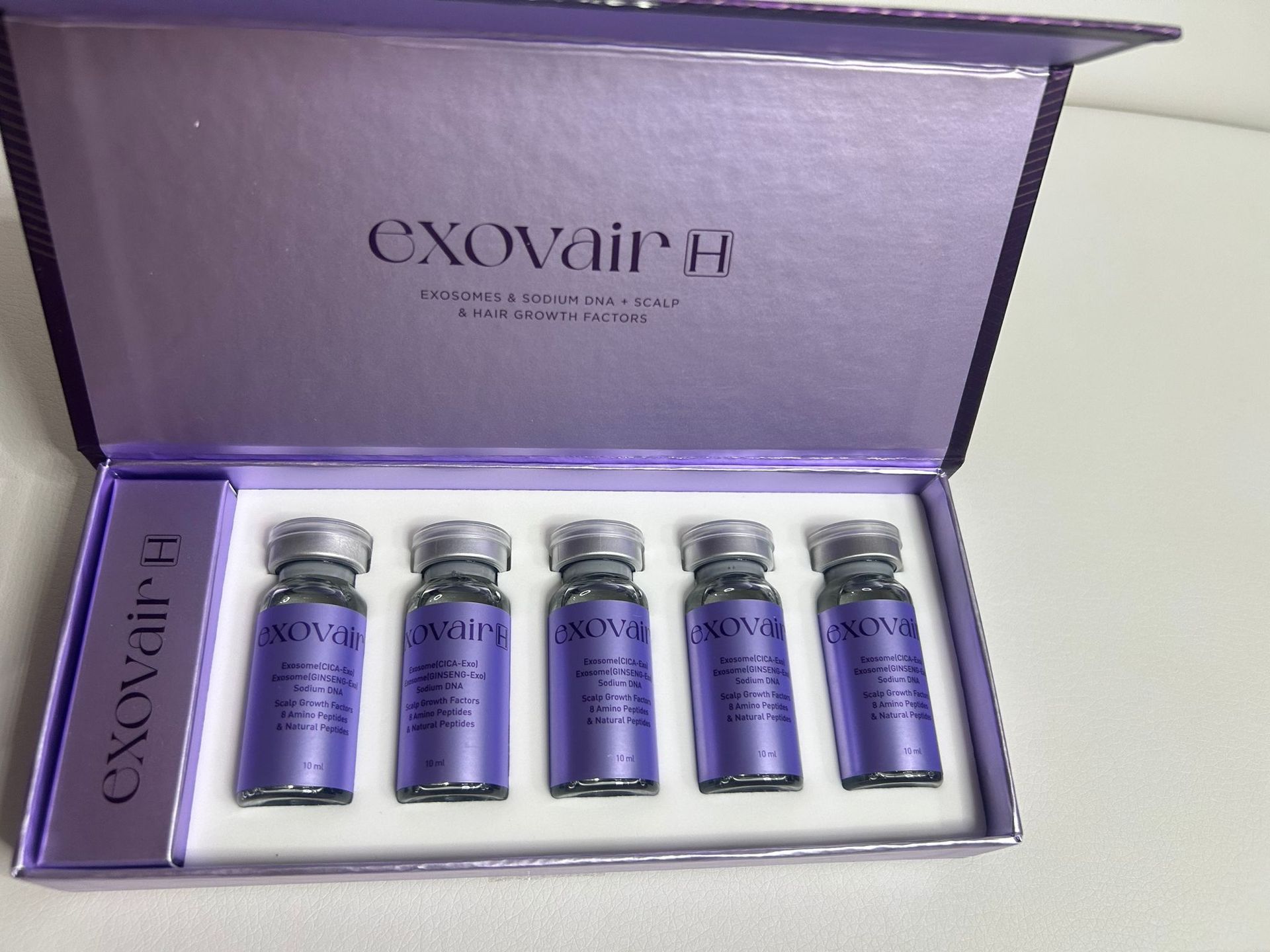 Box of Exovair ampules, purple and silver, on white background. Five ampules inside.