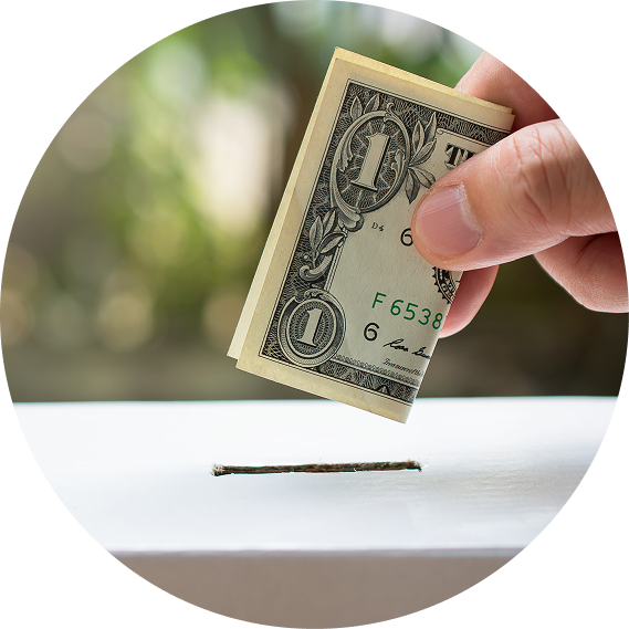 Hand placing a folded dollar bill into a white donation slot