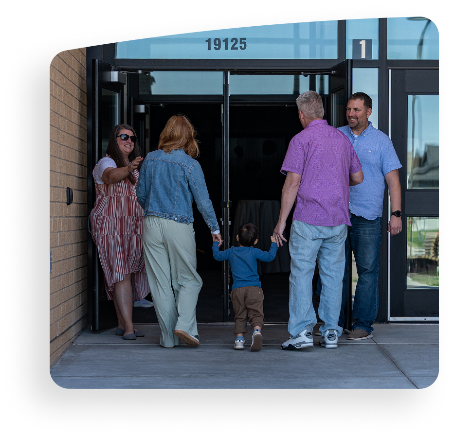 People entering a building, holding a small child’s hands at the doorway.