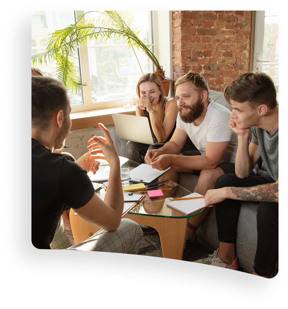 Group meeting around a laptop in a bright office, with notes and coffee on the table.