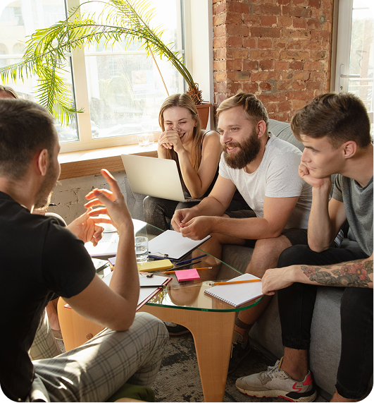 Four people collaborating around a table in a bright office with a laptop and papers