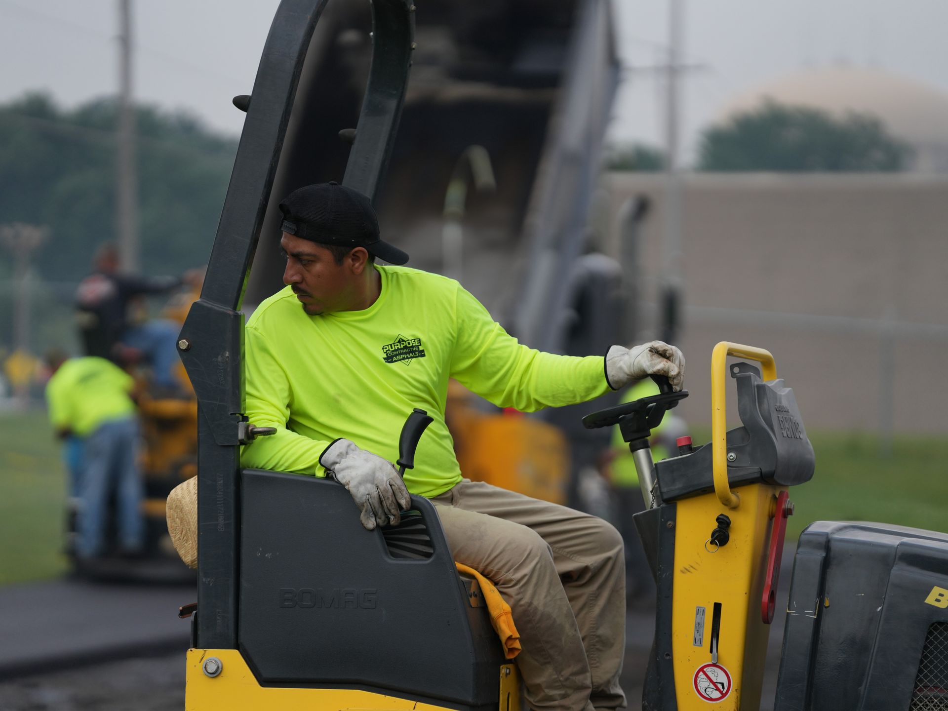 Worker in neon yellow shirt operating a construction machine outdoors