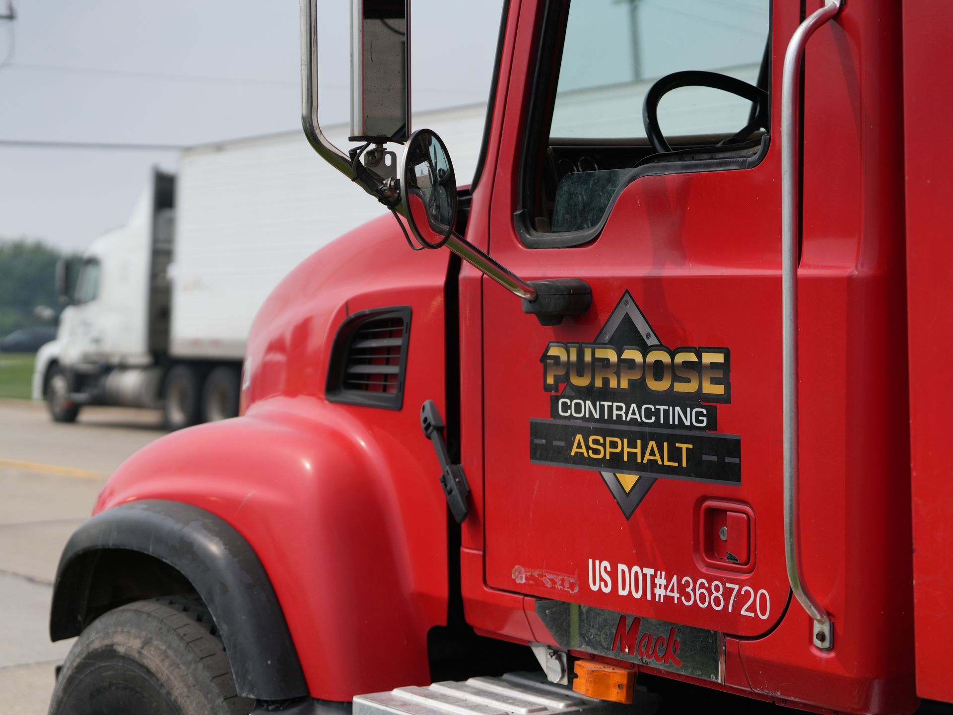 Red asphalt construction truck cab with company logo on the door