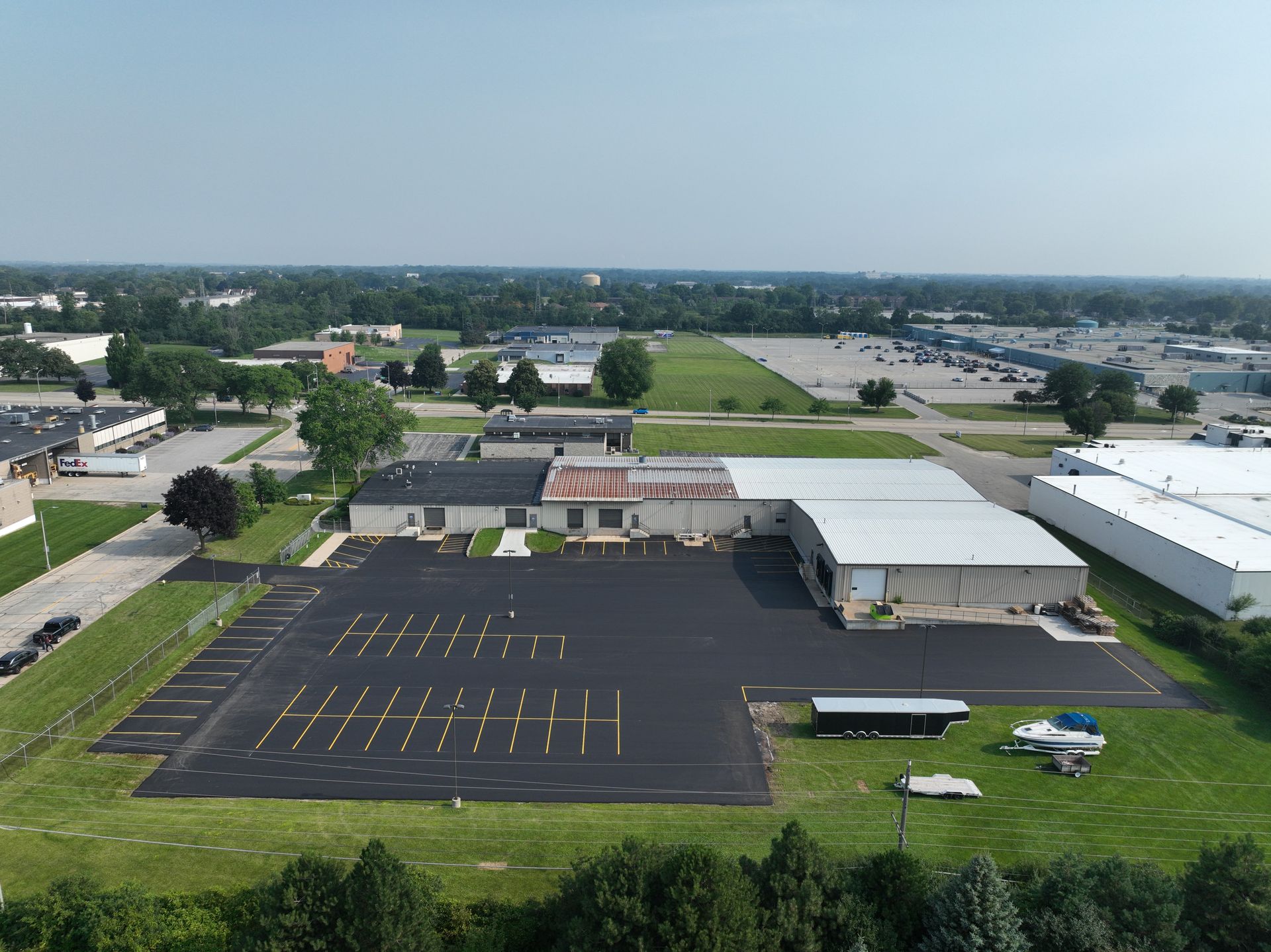 Aerial view of a school parking lot with yellow lines, buses, and buildings on a sunny day