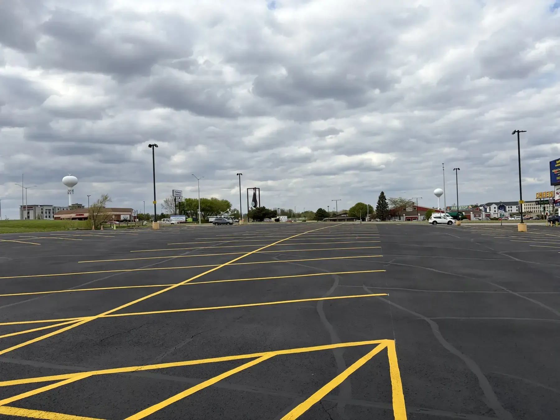 Commercial sealcoating and striping project showing dark asphalt surface, clean parking layout, and high-visibility yellow lines.