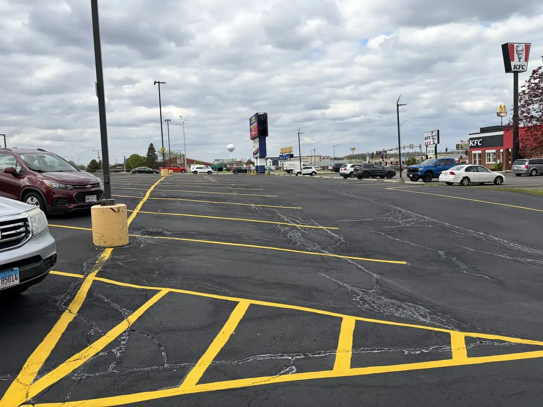 Blacktop parking lot restored with fresh sealcoat and repainted yellow stall lines for improved curb appeal and traffic flow.