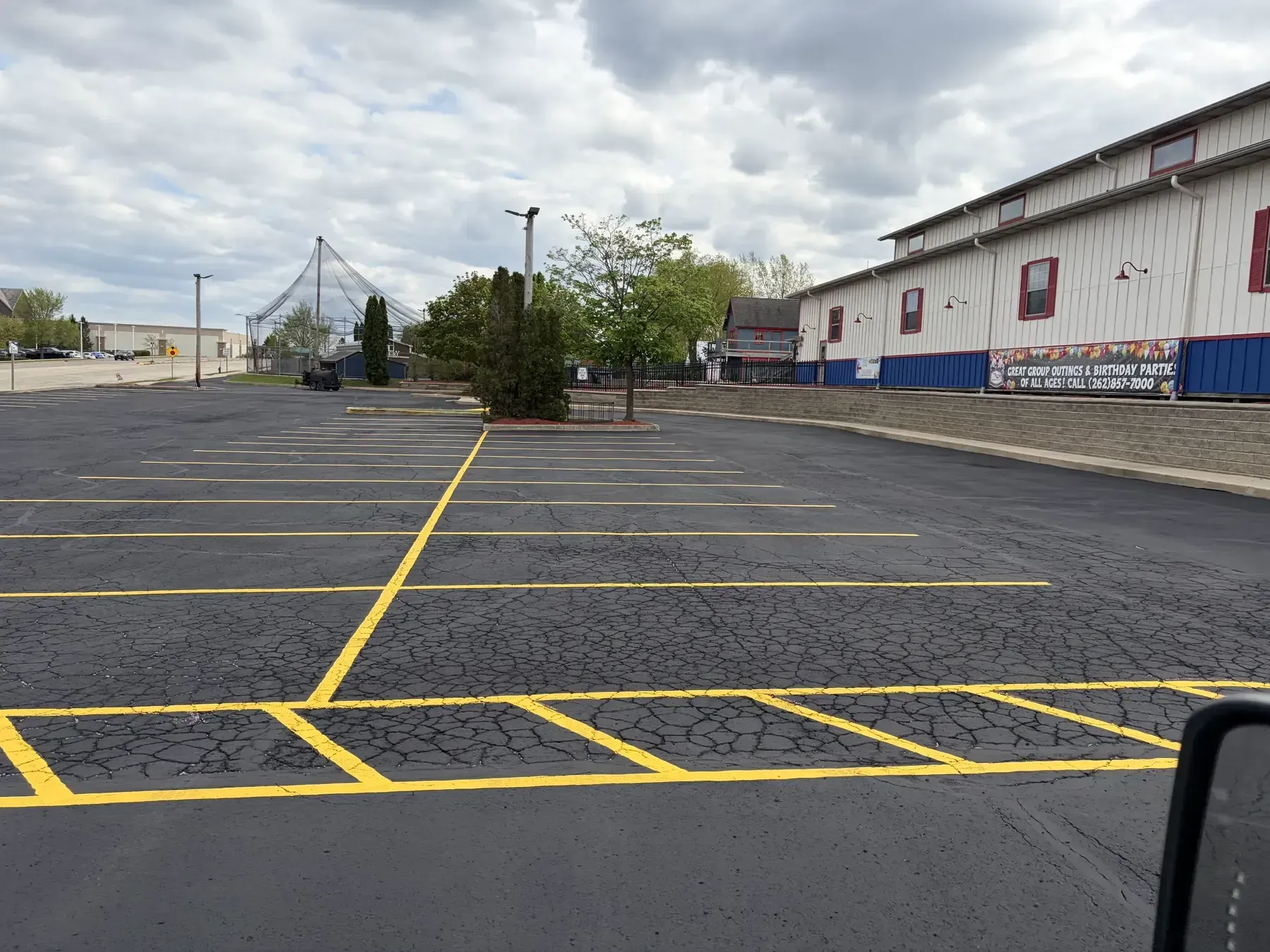 Newly striped asphalt parking lot with sealcoated surface, yellow stall markings, and organized parking layout around commercial buildings.