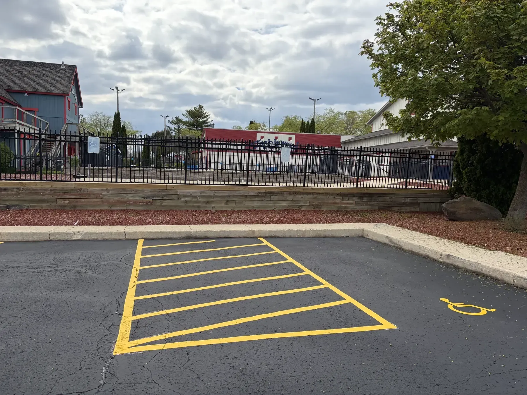 Newly sealcoated asphalt parking area with clean yellow traffic lines, parking stalls, and a handicap access space near a commercial building.
