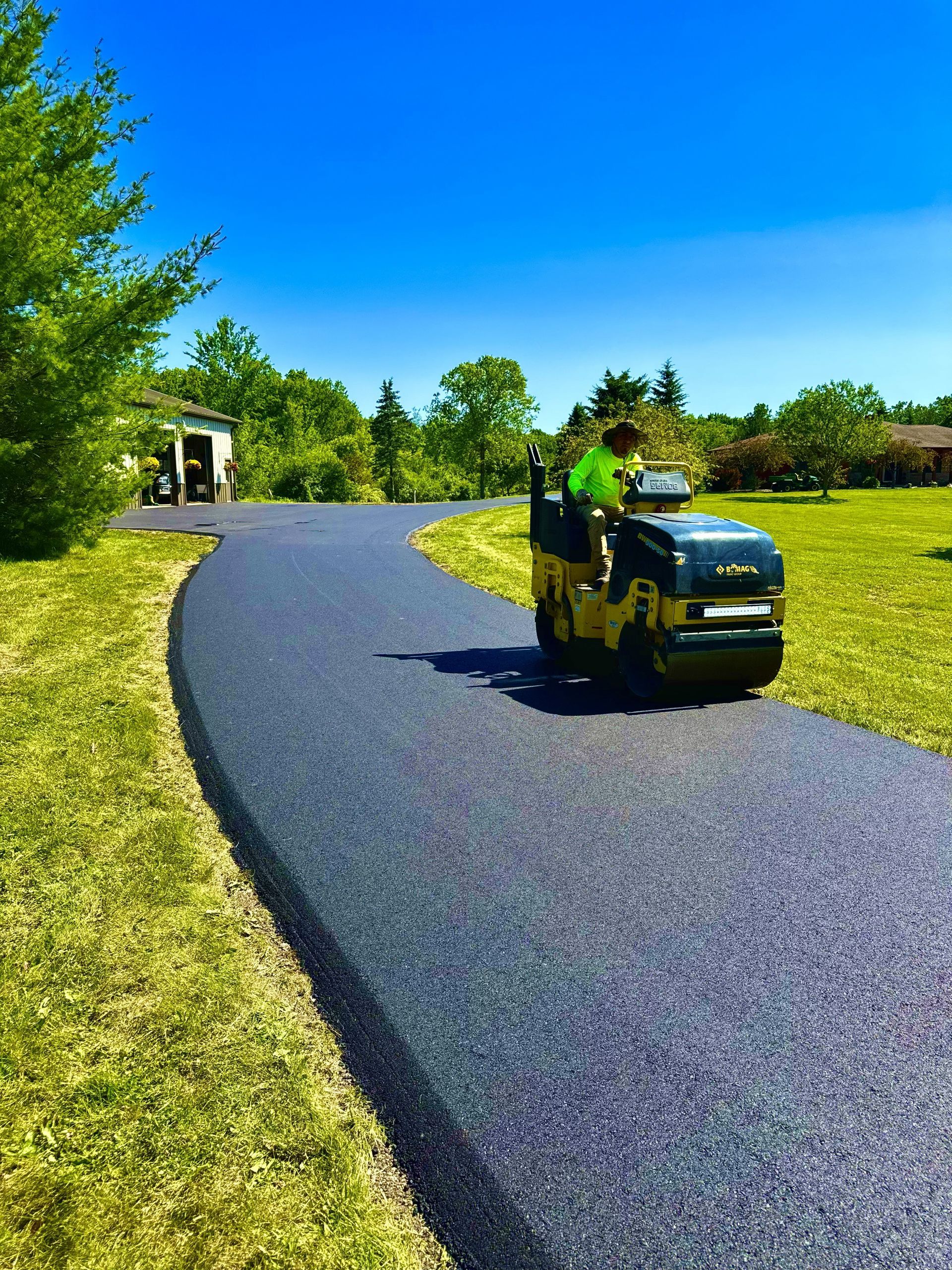Yellow lawn tractor on a curving gravel path in a sunny green park.
