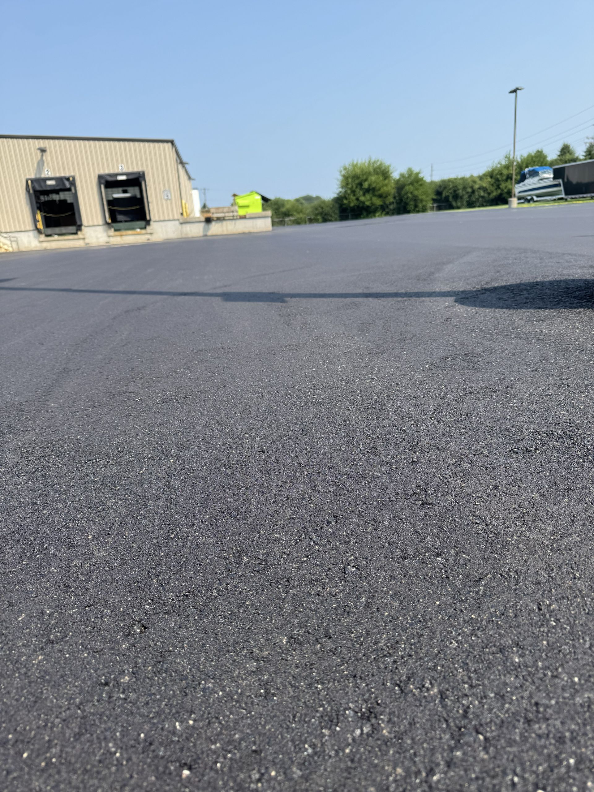 Empty asphalt parking lot beside a beige industrial building on a clear day
