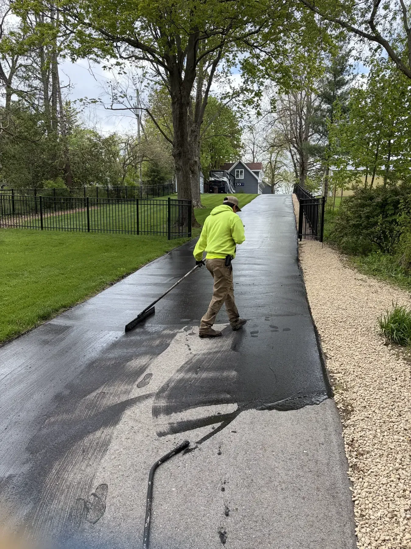 Asphalt paving crew laying blacktop in front of a building on a sunny day.