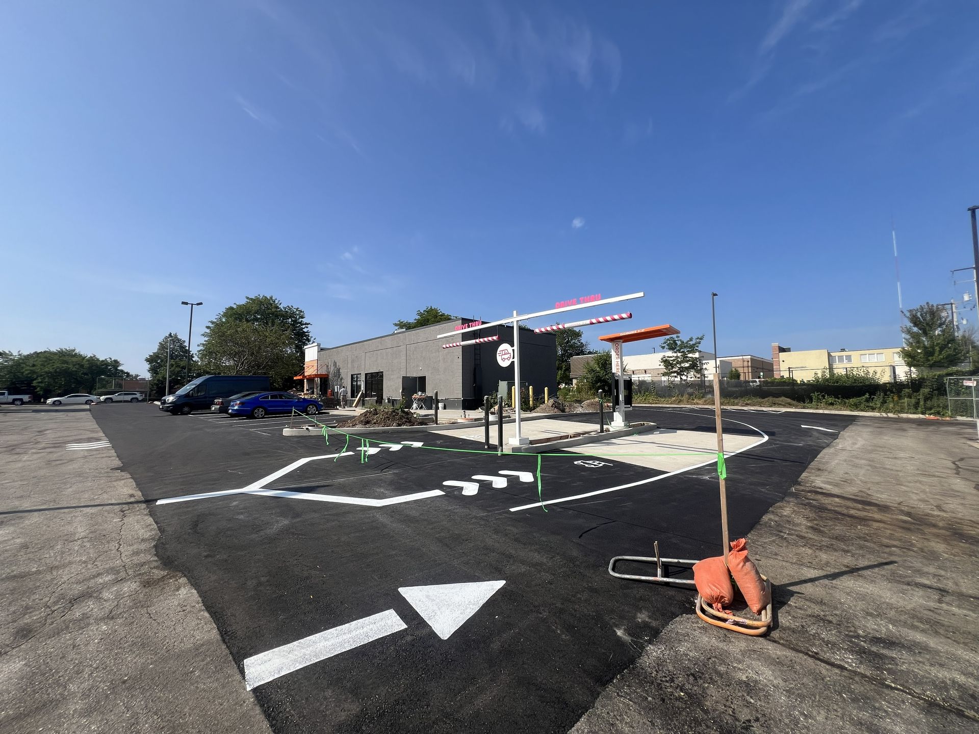 Empty parking lot with white directional arrows, orange cones, and a building under a clear blue sky