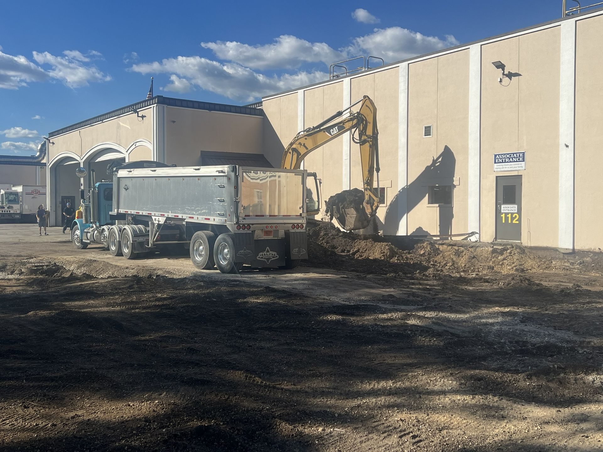 Construction equipment working beside a beige building under a blue sky