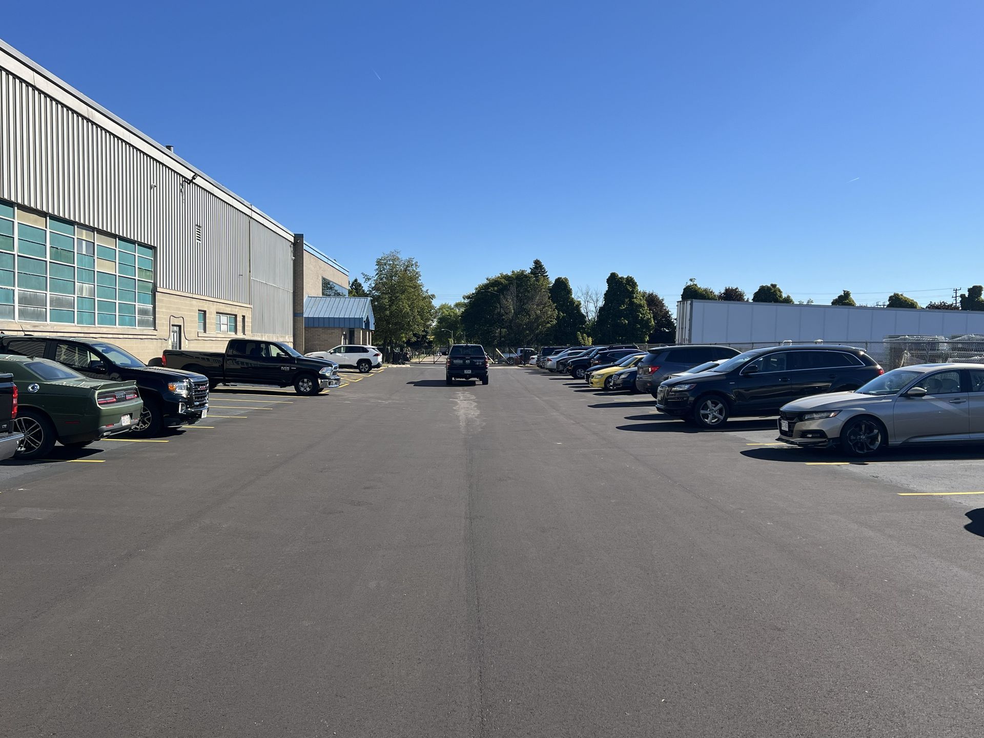 Parking lot beside a large industrial building on a clear sunny day