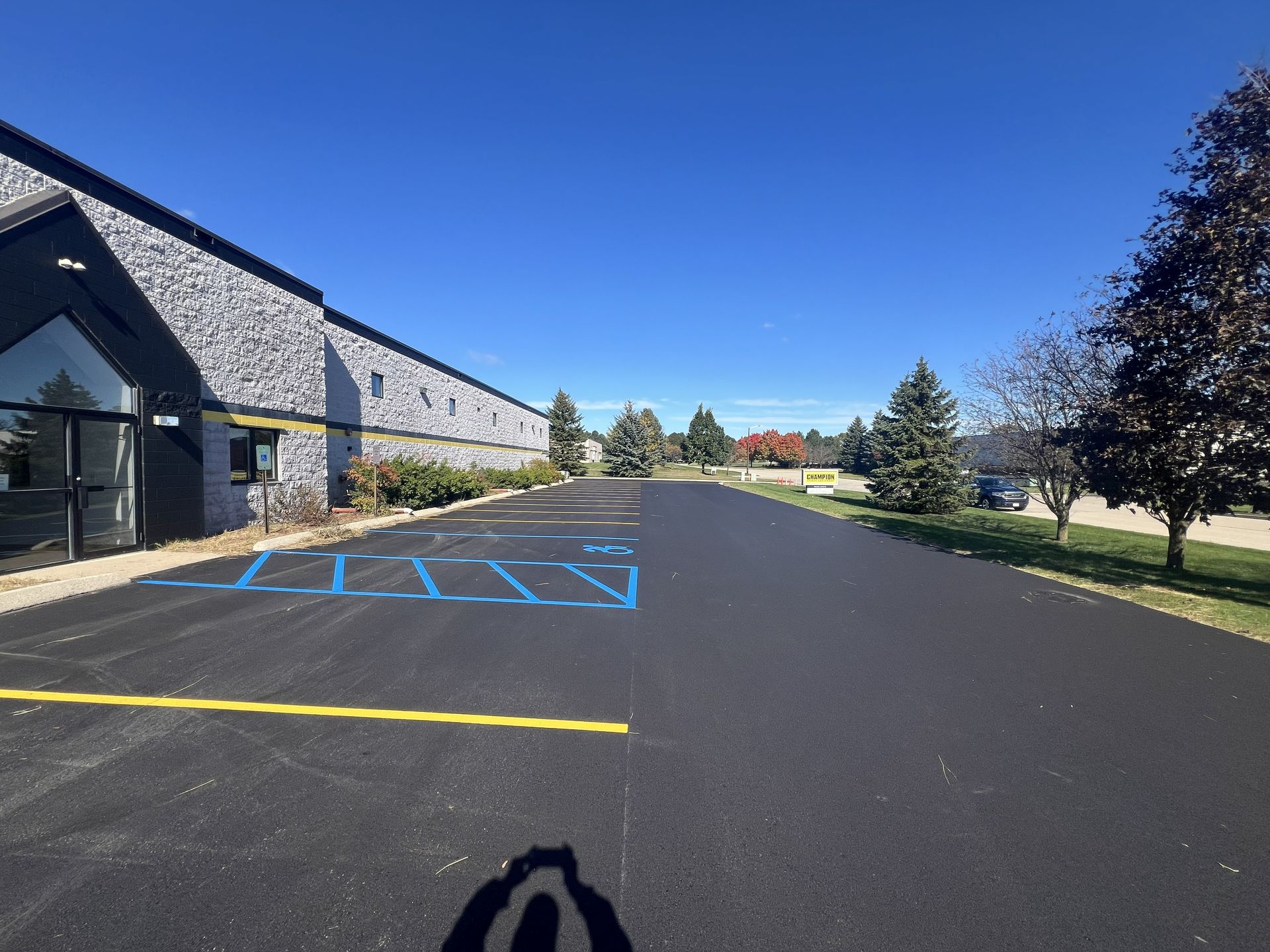 Empty parking lot beside a stone building under a clear blue sky