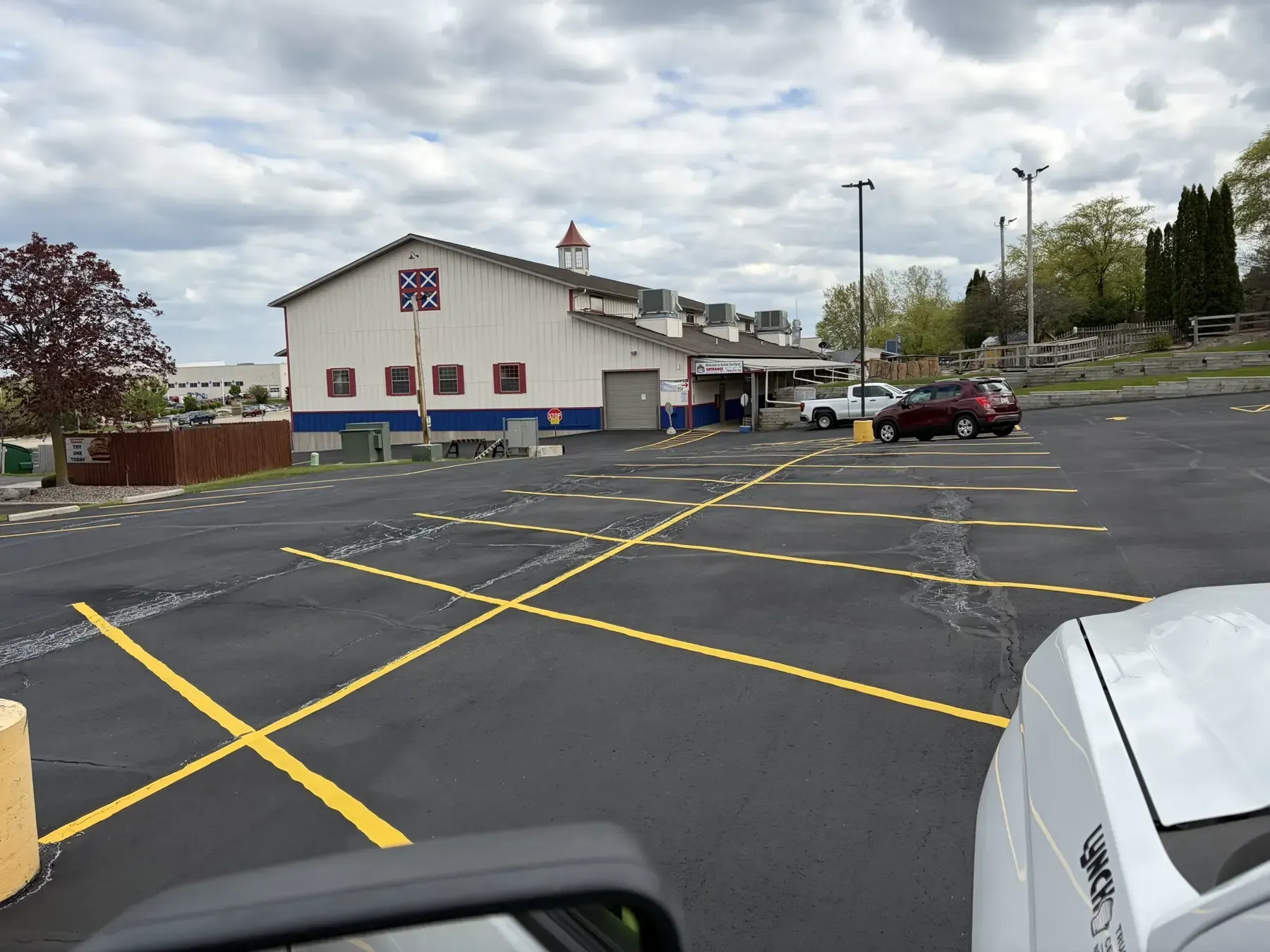 Wide view of a commercial parking lot after sealcoating and line striping with organized parking spaces and drive aisles.