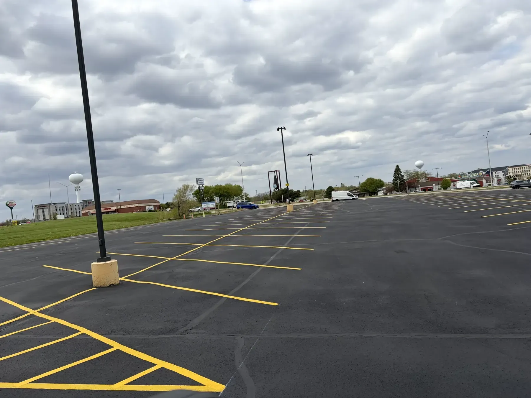 Large commercial parking lot sealcoated and striped with yellow parking stalls, drive lanes, and light pole islands.