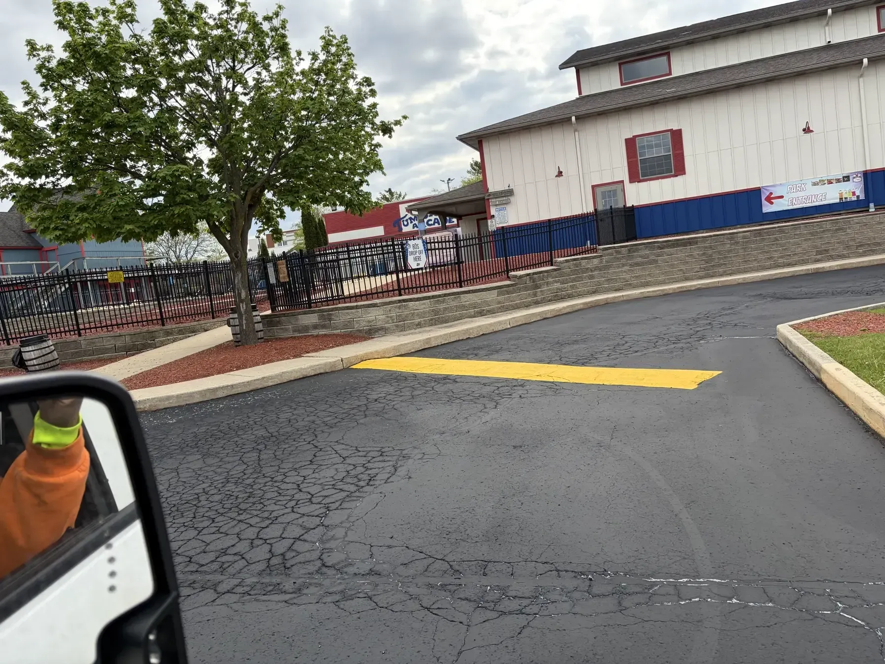 Fresh black sealcoating and crisp yellow parking lot striping beside a large commercial building with marked drive lanes and stalls.