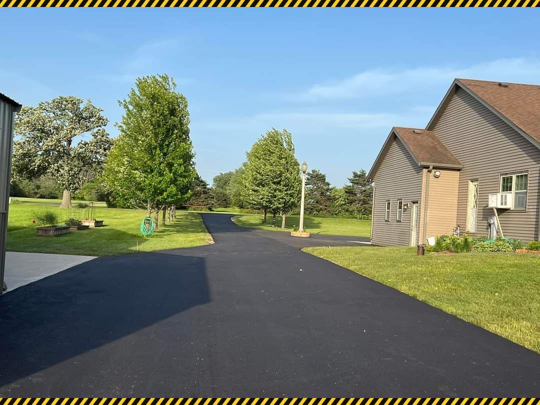 Paved path through a sunny suburban neighborhood with trees, grass, and houses along the road