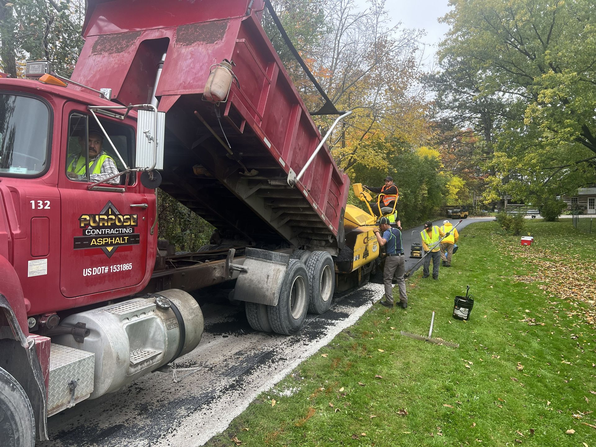 Dump truck overturned on a roadside while firefighters work to clear debris.