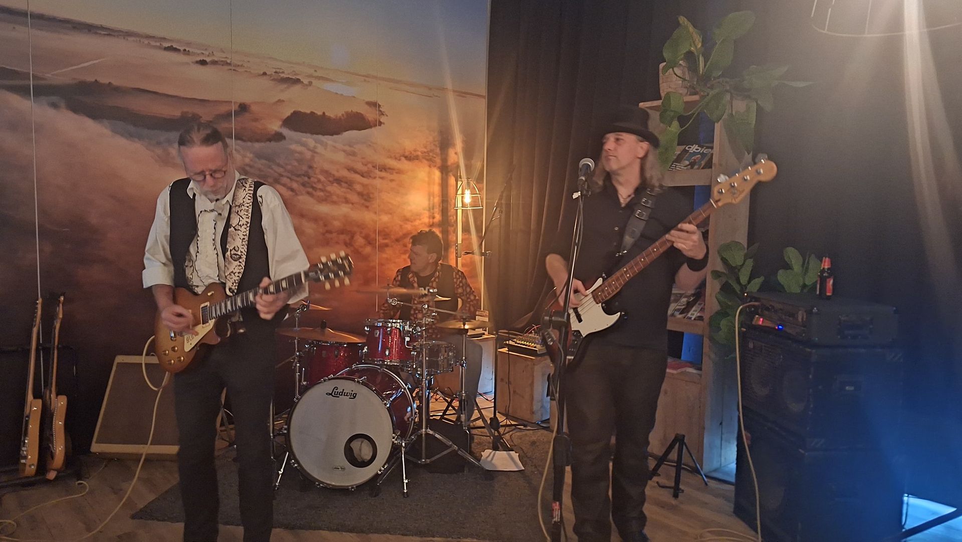 Band die optreedt op het podium: gitarist, bassist, drummer, neutrale achtergrond.