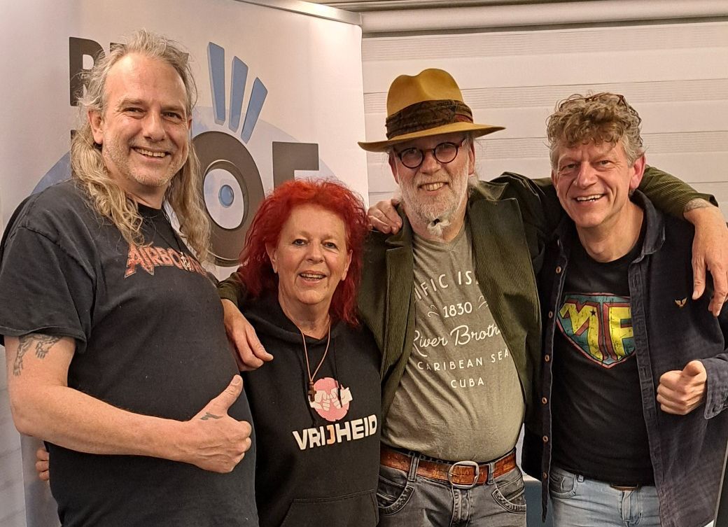 Vier mensen poseren lachend samen.