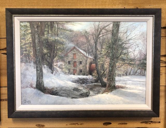 Snowy landscape painting of a farmhouse with bare trees and a stream, framed and mounted on wood.