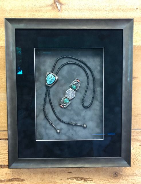 Framed turquoise stone necklace on a black display background