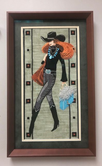 Framed textile artwork of a couple dancing, with an orange jacket and black hat on a patterned background