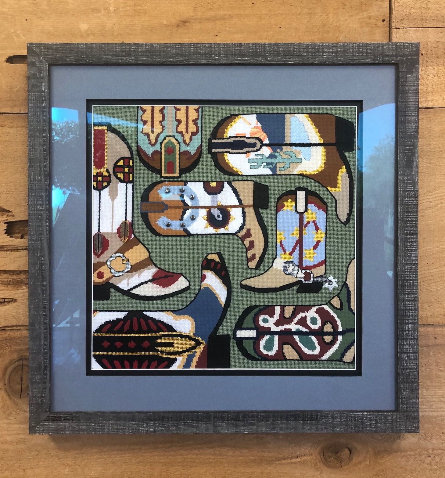 Framed desert cactus painting with bold red, blue, and yellow colors on a wood floor.