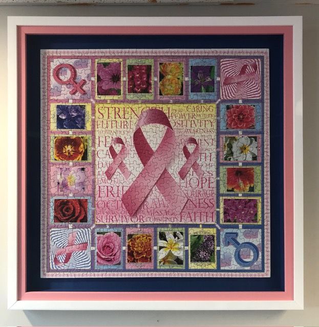 Framed pink ribbon collage quilt with colorful square patches on a pale pink background