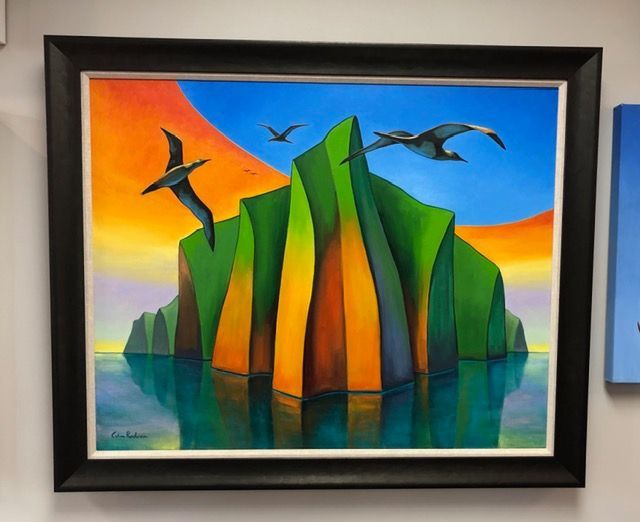 Framed abstract painting of colorful sea stacks with flying birds against a sunrise sky