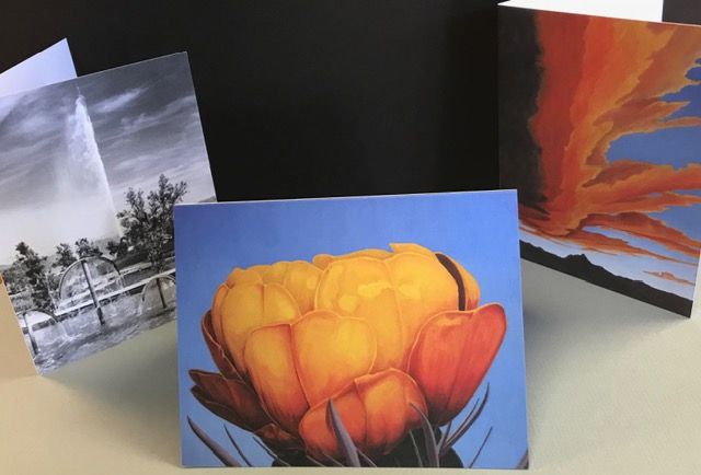 Three small art prints: a yellow flower, a fountain by trees, and an orange-red abstract sunset scene.