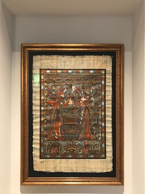 Framed Egyptian-style artwork in gold and black frame on a wall