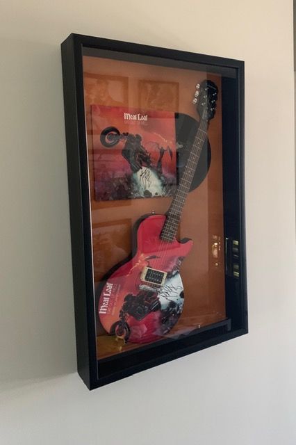 Framed pink electric guitar artwork hanging on a wall