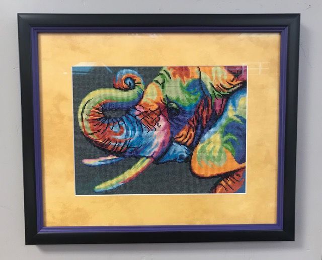Framed abstract colorful swirl painting on a beige mat against a wall