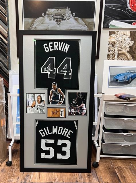 Framed sports memorabilia display with black jersey panels labeled Gerwin 44 and Gilmore 53, plus small photos